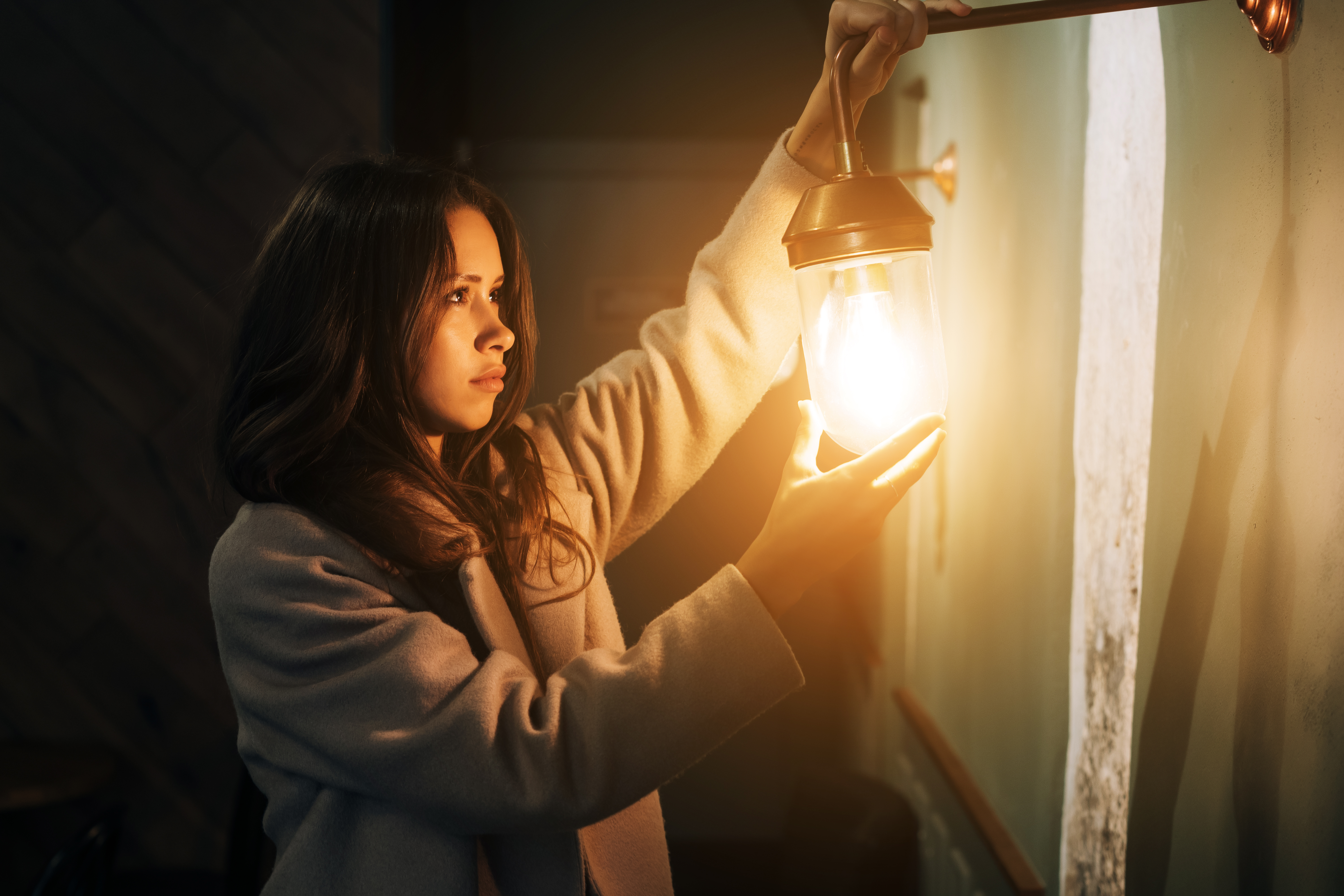 young beautiful woman holds her hand small walllamp