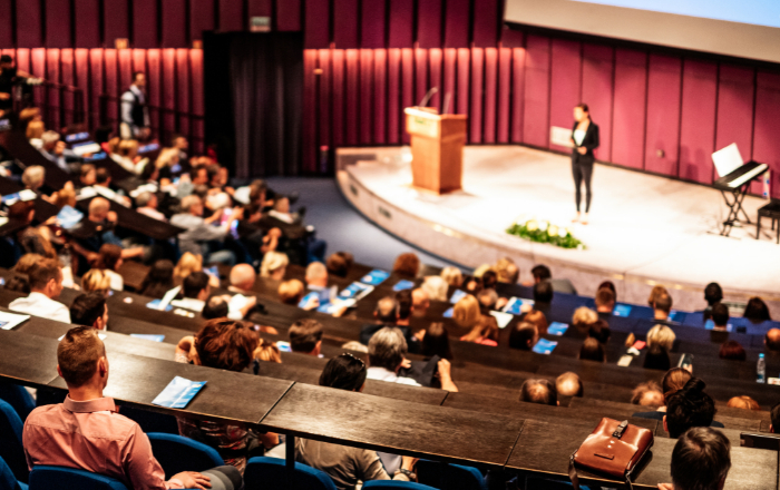 gropup of people listen to a person's talk in a corporate meeting