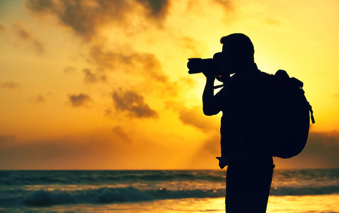 person taking picture of sea in sunset